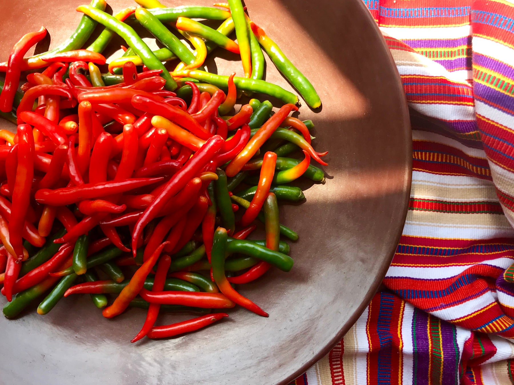 Red and green Mexican chili peppers on a burnished clay plate