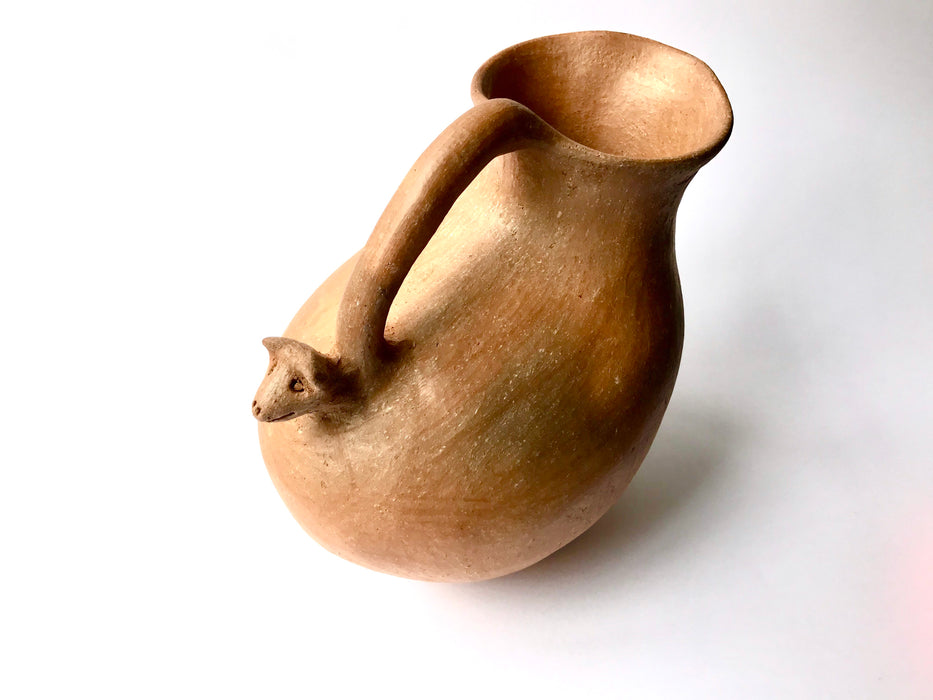 Mexico 1492: Stunning pitcher with an animal head ornament, made from red clay with a yellowish and gray tone and marked with random flame spots, adding character. Best for serving water, refreshing drinks, or even as a vase. Lead free, unglazed. Thanks to the artisanal nature of this handmade product, no two pieces are the same. 