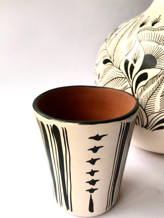 Mexico 1492: The off-white “cántaro” (pitcher), hand made out of clay, hand painted with jewels of the Michoacan nature,  and burnished to shine. Accompanied by a matching glass. Used for storing liquids, like water or wine.   “Cántaro” is a precious piece in every Mexican home, and a favorite way to store water. It is believed that water stays cool in a “cántaro” even on a hottest day.