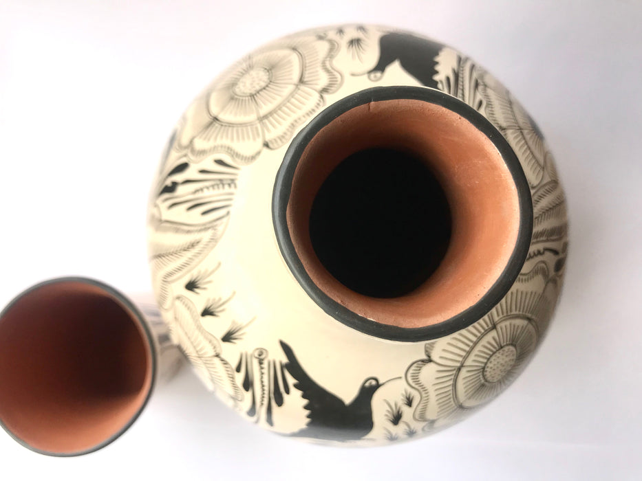 Mexico 1492: The off-white “cántaro” (pitcher), hand made out of clay, hand painted with jewels of the Michoacan nature,  and burnished to shine. Accompanied by a matching glass. Used for storing liquids, like water or wine.   “Cántaro” is a precious piece in every Mexican home, and a favorite way to store water. It is believed that water stays cool in a “cántaro” even on a hottest day.