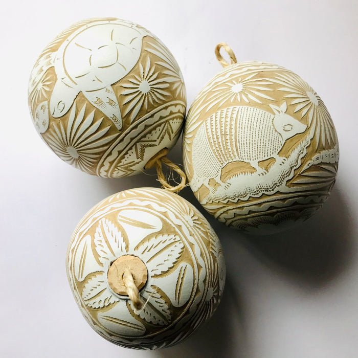 Mexico 1492 - Large, carved, round gourd sphere (guaje), dyed in white and carved by the skillful hands of the Oaxacan artisans. Looks spectacular on a Christmas tree and breathtaking in a pack of 12 or more on a plate or in a bowl. Carved with motifs of birds, armadillos, iguanas and sea turtles. 